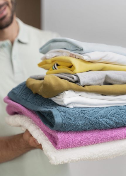 man-holding-pile-clean-clothes